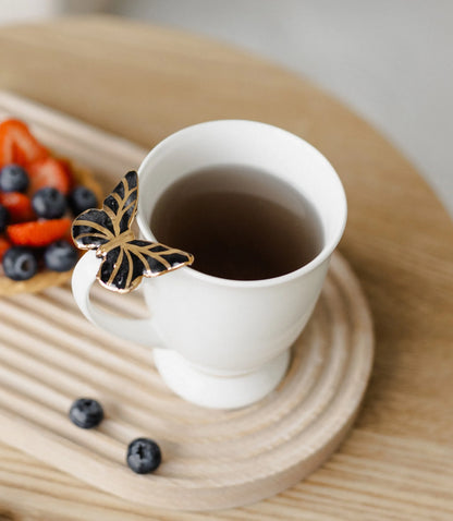 Puodelis su juodu drugeliu