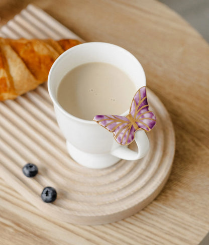 Puodelis su violetiniu drugeliu